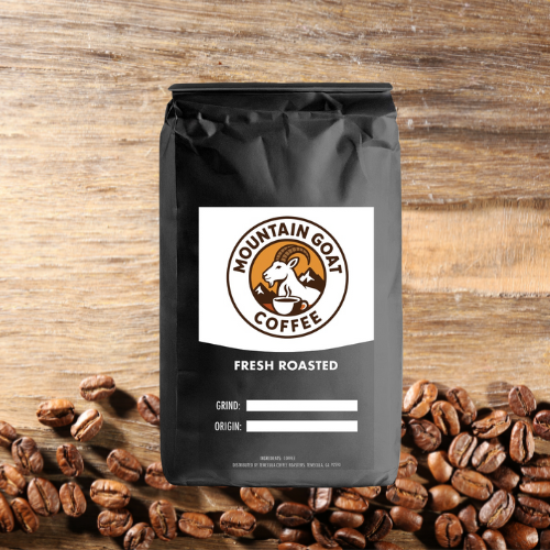Black coffee bag with 'Mountain Goat Coffee' label on a wooden surface with scattered coffee beans
